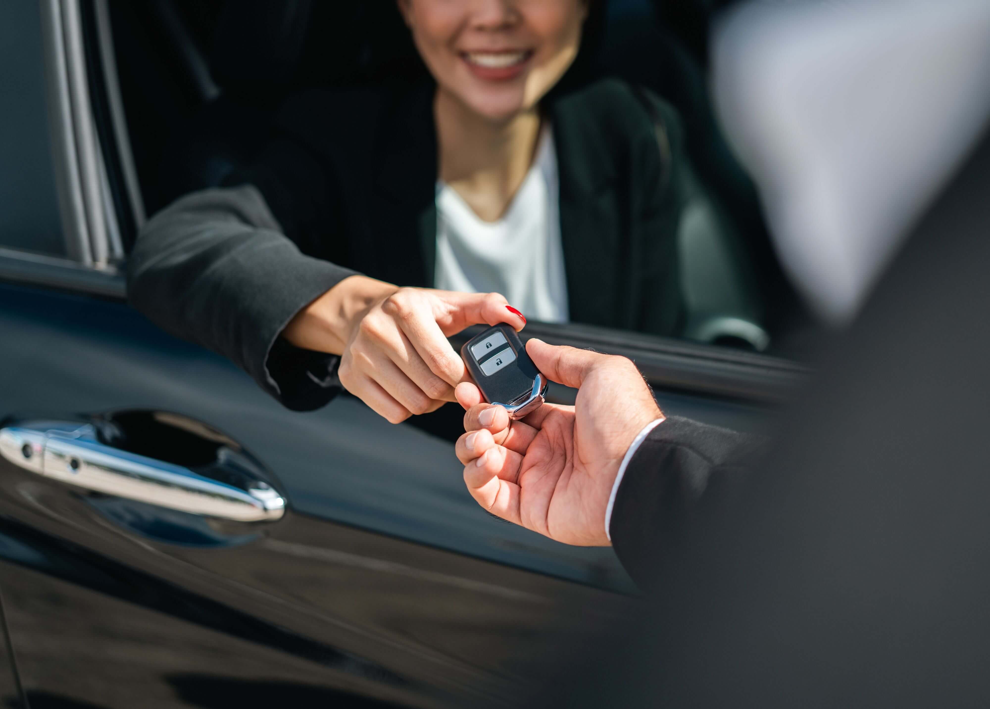 Car dealer handing keys to happy buyer after completing certified used EV purchase